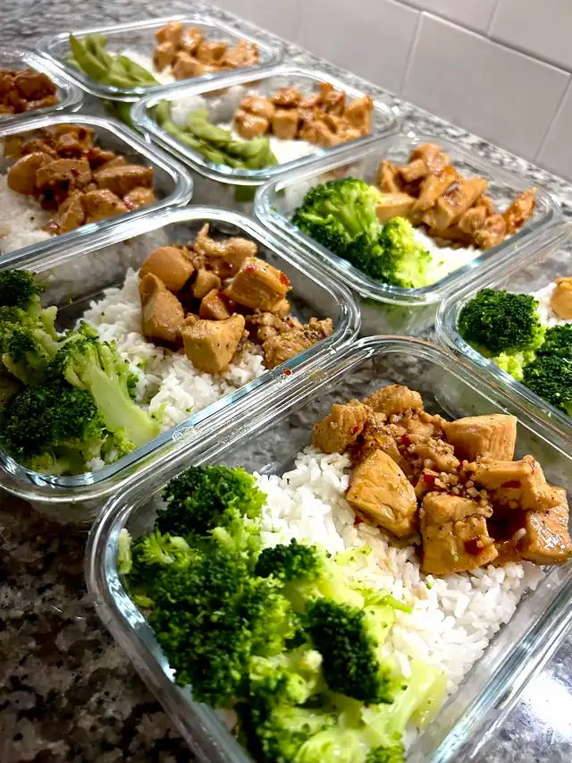 Multiple glass meal prep containers filled with white rice, honey garlic chicken, and steamed broccoli, ready for weekly meals, arranged on a speckled countertop.