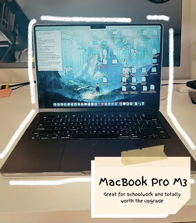 A black MacBook Pro M3 is open on a desk, displaying its screen with a desktop background and various icons, positioned in front of a computer monitor.
