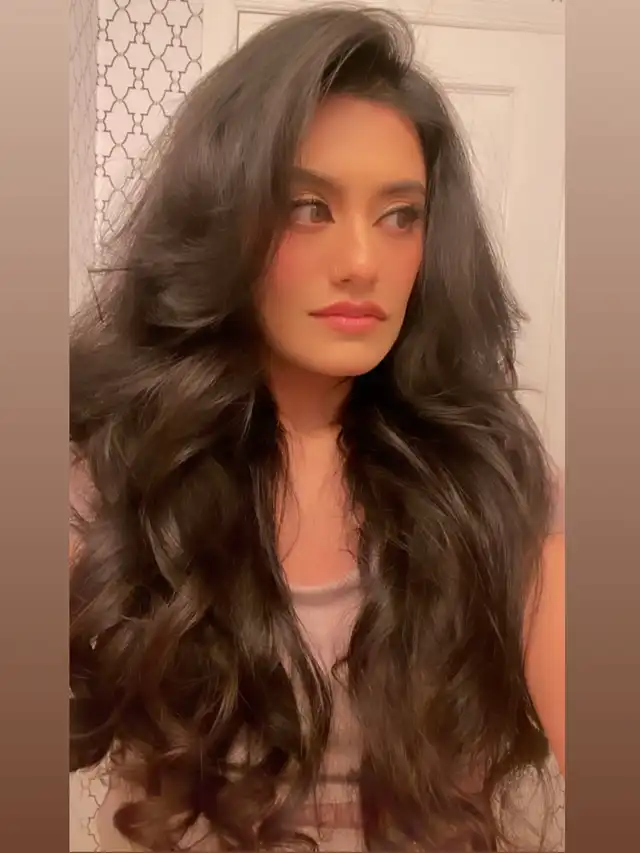 A woman with long, voluminous, dark, wavy hair, showcasing the final results of hair loss reversal. Her hair appears healthy, shiny, and full, demonstrating a successful hair transformation.
