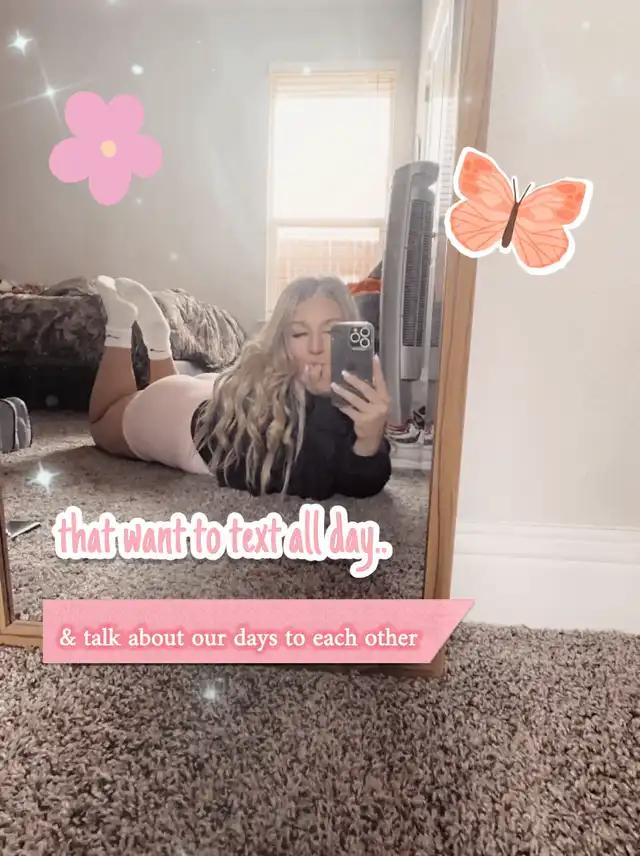 A young woman with blonde hair lies on a carpeted floor, taking a mirror selfie and sticking out her tongue. Text overlay says "that want to text all day. & talk about our days to each other," expressing a desire for constant communication with new friends.