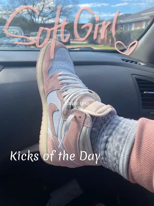 A person's foot, wearing a pink and white high-top sneaker with grey socks, rests on a car dashboard. The background shows a street scene. Text overlays include 'Soft Girl' and 'Kicks of the Day'.