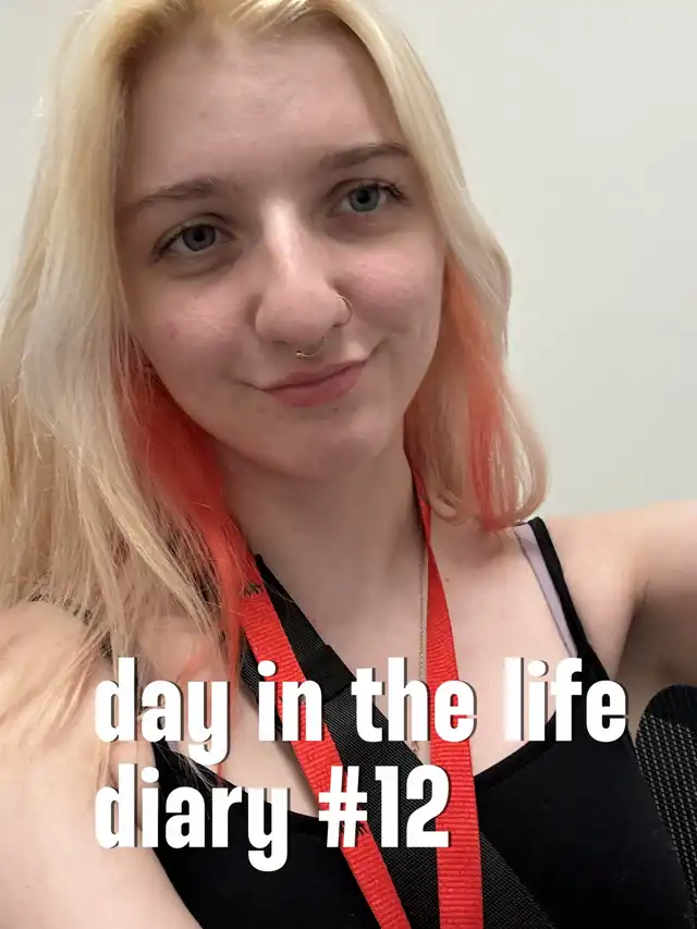 A young woman with blonde hair and orange streaks, wearing a black top and red lanyard, smiles at the camera. The image has a text overlay that reads "day in the life diary #12."