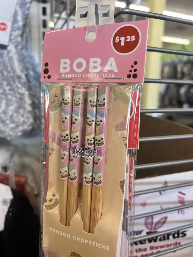 A package of bamboo chopsticks with a pink design featuring cartoon boba tea cups, labeled 'Boba'. The package is hanging on a store rack, presented as a budget-friendly item.