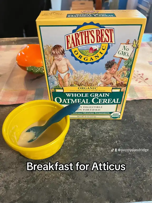 A box of organic whole grain oatmeal cereal and a yellow bowl with baby food and a spoon, prepared for "Breakfast for Atticus."