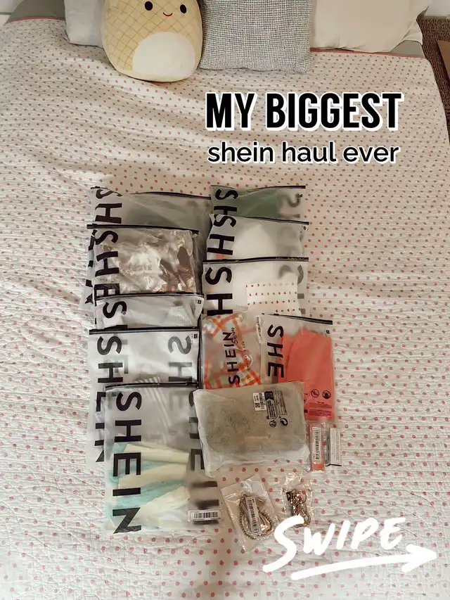 A flat lay of numerous Shein packages, indicating a large clothing haul, on a white bedspread with pink polka dots. Text overlays announce 'MY BIGGEST shein haul ever' and 'SWIPE'.